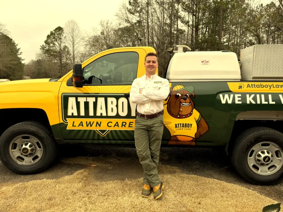 Tyler from Attaboy Lawn Care with branded service truck